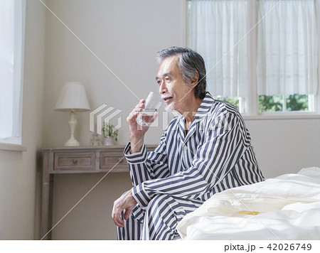 ベッドに座って水を飲むシニア男性 42026749