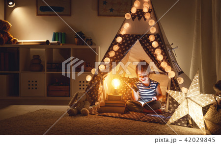 happy child girl laughing and reading book in dark in tent at ho happy child girl laughing and reading book in dark in tent at ho 42029845