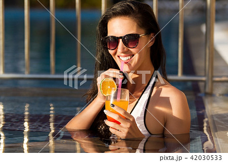 beautiful smiling woman drinking a cocktail in a pool 42030533
