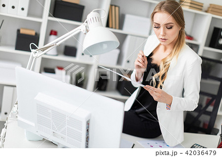 The young girl sat down on the desk in the office and worked with a computer and documents. 42036479