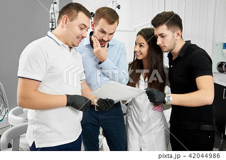 Dentist and his assistant show patients instructions for dental care 42044986