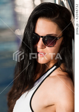portrait of a woman leaning on the metal fence of a pool portrait of a woman leaning on the metal fence of a pool 42048732