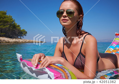 A beautiful young girl lies on a mattress in the open sea A beautiful young girl lies on a mattress in the open sea 42051362