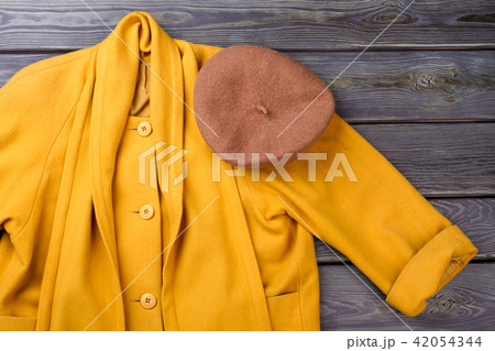Close up brown beret hat on yellow coat. 42054344