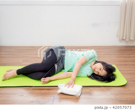 Young woman practicing yoga, lying on green mat. 42057073