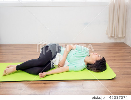 Young woman practicing yoga, lying on green mat. Young woman practicing yoga, lying on green mat. 42057074