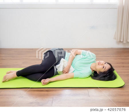Young woman practicing yoga, lying on green mat. 42057076