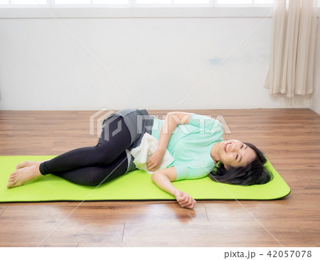 Young woman practicing yoga, lying on green mat. 42057078