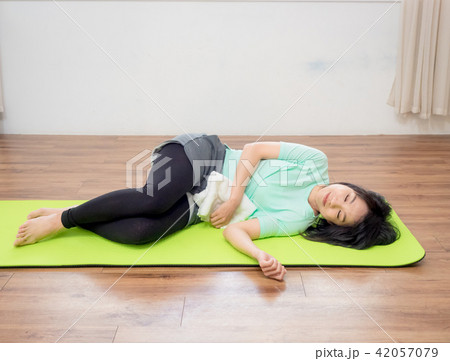 Young woman practicing yoga, lying on green mat. 42057079