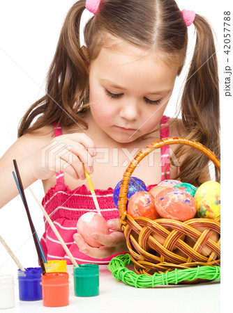 Little girl is painting eggs preparing for Easter Little girl is painting eggs preparing for Easter 42057788
