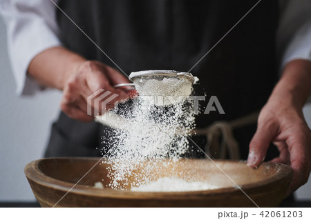 Female hands sifting flour to bowl. 42061203