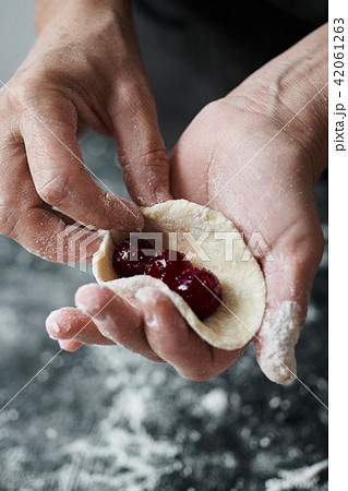 Woman cook manually sculpts dumplings stuffed with cherries 42061263