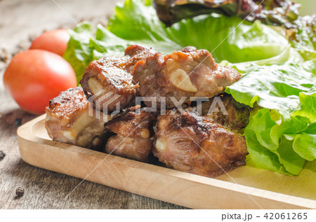 Fired pork rips on wooden plate with vegetable. 42061265