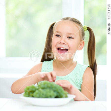 Cute little girl is eating green grapes 42061790