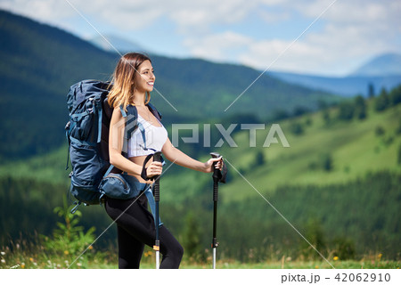 Sporty woman hiker with backpack and trekking sticks hiking in the mountains 42062910