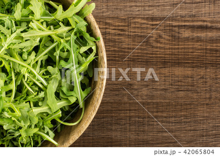 Fresh Raw Arugula (rucola) on brown wood Fresh Raw Arugula (rucola) on brown wood 42065804
