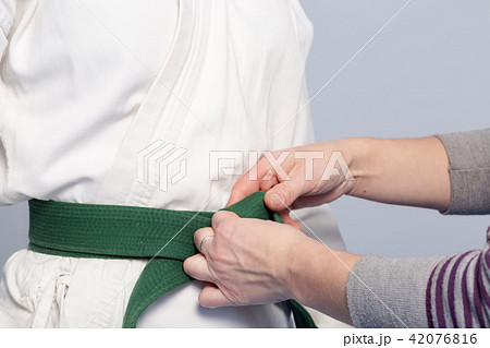 Hands of a parent who helps a child to tie a belt 42076816