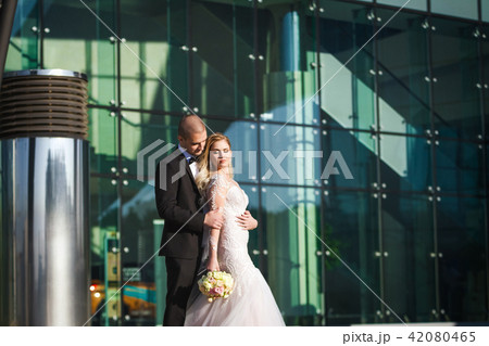 bride and groom holding each other near futuristic building bride and groom holding each other near futuristic building 42080465