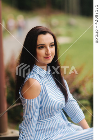 Lady in blue dress sitting on the bench near the lake 42083151