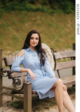 Lady in blue dress sitting on the bench near the lake 42083156