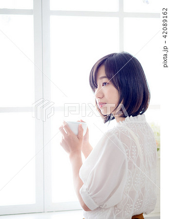 woman standing in front of window and drink coffee 42089162