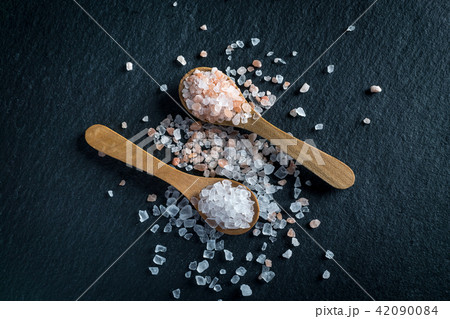 Two wooden spoons with pink himalayan and white kithchen salt 42090084