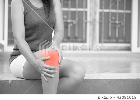 Woman feeling pain in her knee at home Woman feeling pain in her knee at home 42091018