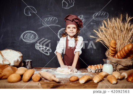 Little girl kneading dough at table Little girl kneading dough at table 42092563