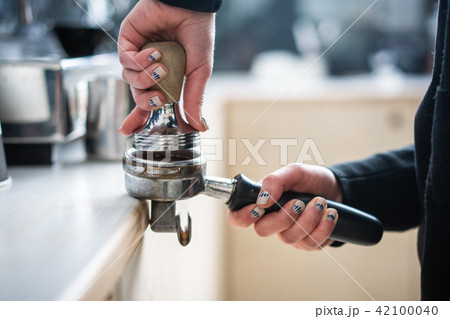 Barista presses ground coffee using tamper. 42100040
