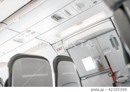 Emergency exit on an aircraft, view from inside of the plane. Empty airplane seats in the cabin 42105399
