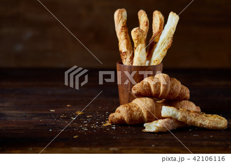 Puff pastries on piece of board over dark wooden table, close-up, selective focus, backlight. 42106116