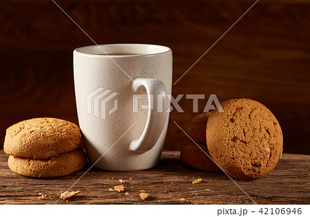 White porcelain mug of tea and sweet cookies on piece of wood over wooden background, top view 42106946