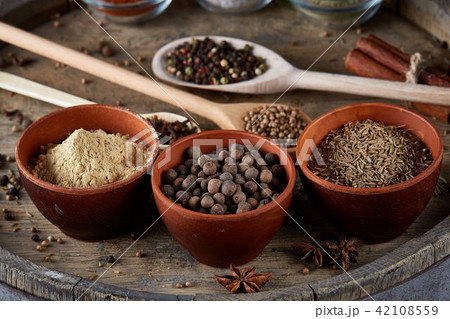 Various spices in wooden spoons and bowls on an old wooden barrel, top view, close-up, selective 42108559