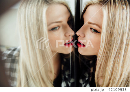 portrait of beautiful young woman blonde girl and her reflection in mirror. portrait of beautiful young woman blonde girl and her reflection in mirror. 42109933