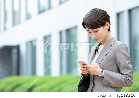 携帯電話を操作するスーツの女性　オフィスレディ　新緑　OL　ビジネス　スーツ　ポートレート 42113316