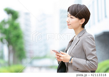 携帯電話を操作するスーツの女性　オフィスレディ　新緑　OL　ビジネス　スーツ　ポートレート 42113318
