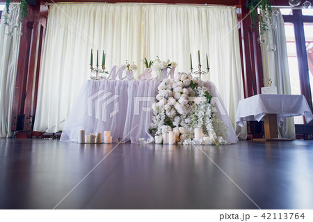 Flower garland of pine-shaped roses hangs from the table. Wedding decoration, floristry. Candelabra 42113764