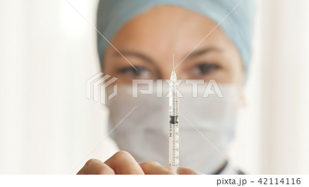 A woman doctor prepares a syringe for a shot. A woman doctor prepares a syringe for a shot. 42114116