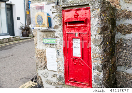 石壁の中に埋め込まれたイギリスの赤いポスト イギリス西端の田舎町にての写真素材