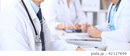 Unknown male doctor is sitting at the table and working in the hospital office. Closeup of 42117699