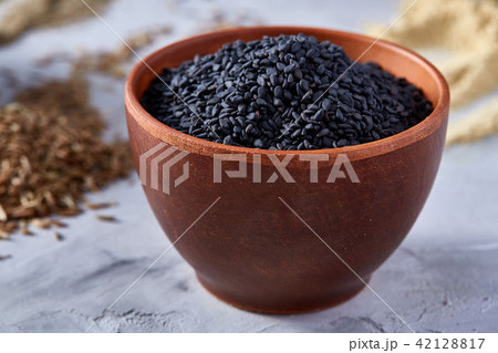 Black sesame seeds in a clay bowl on white textured background, close-up, top view. Black sesame seeds in a clay bowl on white textured background, close-up, top view. 42128817