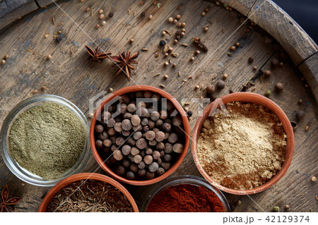 Spices in ceramic bowls on the top of wooden barrel, close-up, selective focus, vertical. Spices in ceramic bowls on the top of wooden barrel, close-up, selective focus, vertical. 42129374
