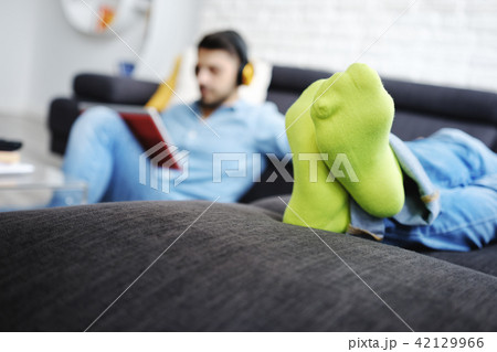 Couple Lying On Sofa With Tablet PC and Earphones Couple Lying On Sofa With Tablet PC and Earphones 42129966
