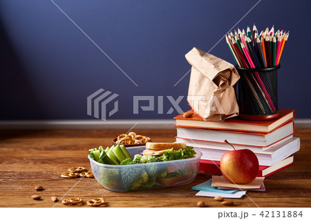 Concept of school lunch break with healthy lunch box and school supplies on white desk, selective Concept of school lunch break with healthy lunch box and school supplies on white desk, selective 42131884