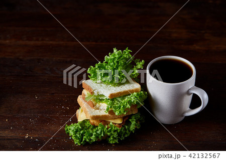 Breakfast table with sandwich and black coffee on rustic wooden background, close-up, selective 42132567