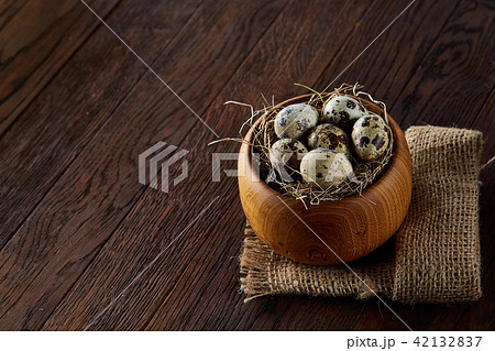 Fresh quail eggs in a wooden bowl on a dark wooden background, top view, close-up Fresh quail eggs in a wooden bowl on a dark wooden background, top view, close-up 42132837
