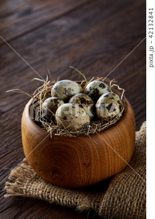 Fresh quail eggs in a wooden bowl on a dark wooden background, top view, close-up Fresh quail eggs in a wooden bowl on a dark wooden background, top view, close-up 42132841
