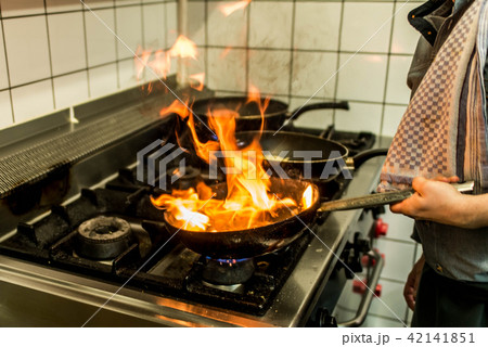 restaurant Chef cooking with flame in a frying pan on a kitchen stove restaurant Chef cooking with flame in a frying pan on a kitchen stove 42141851