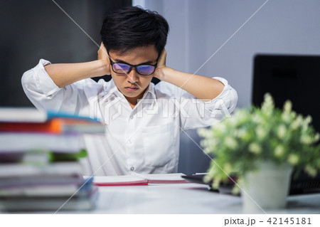 student reading book and closing ears with both hands, stressed 42145181