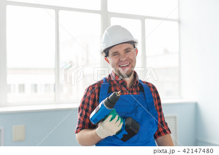 Happy caucasian male builder with drill wearing white helmet. Happy caucasian male builder with drill wearing white helmet. 42147480